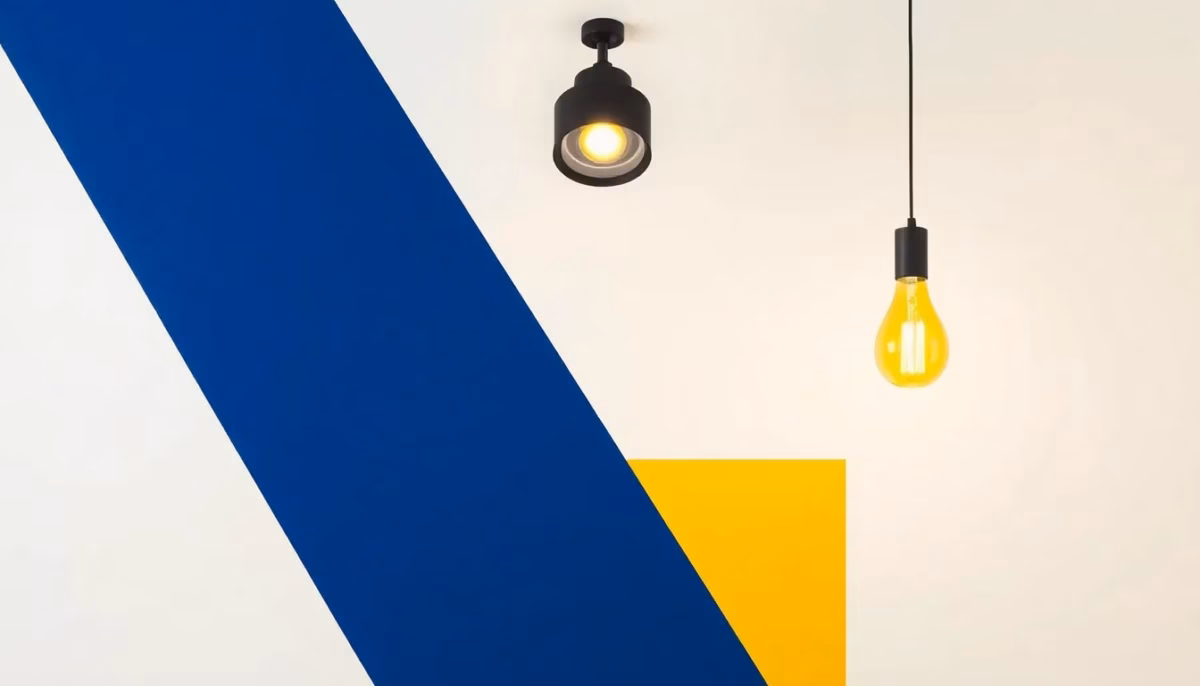 Suprematist abstract painting by Kazimir Malevich featuring a modern ceiling spot light and warm glowing pendant lamp. Minimalist composition of bold navy blue and vibrant yellow geometric shapes on a stark white background. Flat textures, sharp edges, avant-garde electrical concept. ##no humans##, ##no text##.