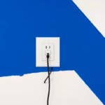 Suprematist abstract painting by Kazimir Malevich featuring a grounding rod and electrical outlet. Minimalist composition of bold navy blue and vibrant yellow geometric shapes on a stark white background. Flat textures, sharp edges, avant-garde electrical concept. No humans, no text.
