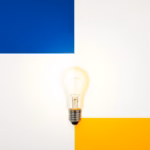 Suprematist abstract painting in the style of Kazimir Malevich, featuring a glowing LED bulb and a vintage incandescent bulb side by side, radiating geometric beams of light. Minimalist composition of bold navy blue and vibrant yellow geometric shapes on a stark white background. Flat textures, sharp edges, avant-garde electrical concept celebrating energy savings. No humans, no text, no text overlay.