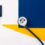 Suprematist abstract painting in the style of Kazimir Malevich featuring a large round 32-amp electrical socket with a heavy cooker plug and thick cable. Minimalist composition of bold navy blue and vibrant yellow geometric shapes on a stark white background. Flat textures, sharp edges, avant-garde electrical concept. No humans, no text overlay.