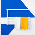 Suprematist abstract painting by Kazimir Malevich featuring a wall-mounted electric towel radiator with two towels hanging in a bathroom. Minimalist composition of bold navy blue and vibrant yellow geometric shapes on a stark white background. Flat textures, sharp edges, avant-garde electrical product concept. No people, no text.