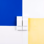 Suprematist abstract painting in the style of Kazimir Malevich representing a magnetic door and window contact sensor, split into two aligned rectangular blocks facing each other on a narrow vertical frame. Minimalist composition of bold navy blue and vibrant yellow geometric shapes on a stark white background. Flat textures, sharp edges, avant-garde electrical concept, clean studio lighting. No humans, no text, no lettering, no overlay.