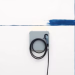 Suprematist abstract painting by Kazimir Malevich featuring a wall-mounted electric vehicle charging station with a coiled Type 2 cable. Minimalist composition of bold navy blue and vibrant yellow geometric shapes on a stark white background. Flat textures, sharp edges, avant-garde electrical concept. No humans, no text.